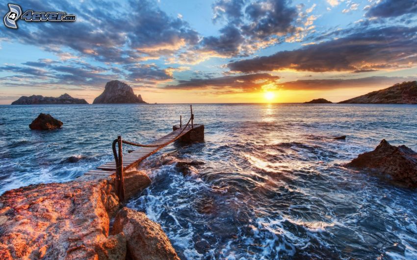 wooden pier, sea, sunset behind the sea, rocks in the sea