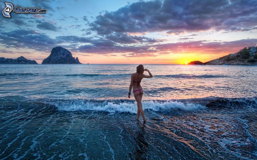 sexy woman in swimsuit, sunset behind the sea, clouds